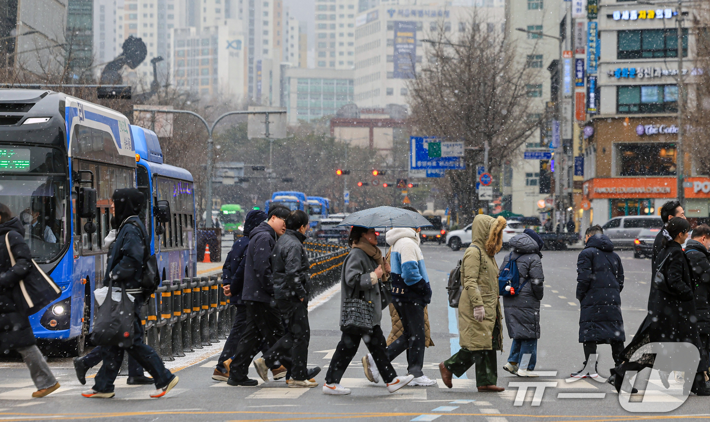 (서울=뉴스1) 이호윤 기자 = 눈이 내리는 12일 서울 세종대로사거리에서 시민들이 발걸음을 옮기고 있다. 2026.1.12/뉴스1