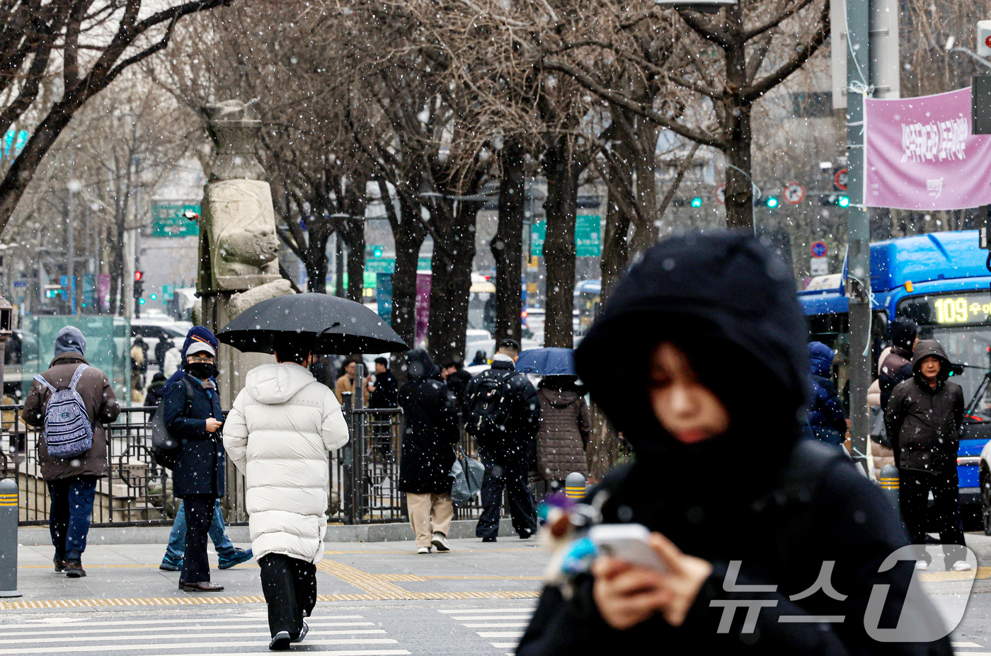(서울=뉴스1) 이호윤 기자 = 눈이 내리는 12일 서울 세종대로사거리에서 시민들이 발걸음을 옮기고 있다. 2026.1.12/뉴스1