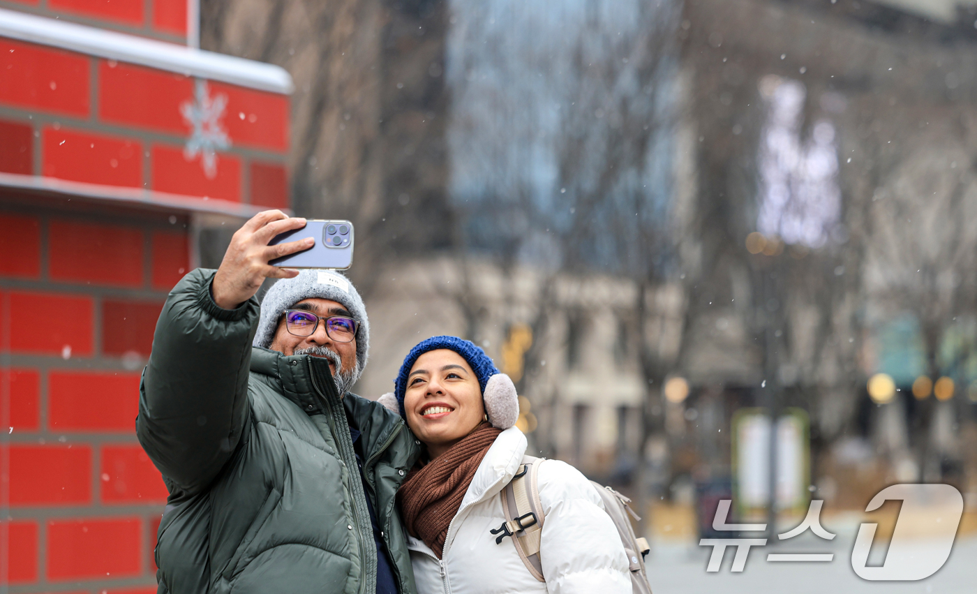 (서울=뉴스1) 이호윤 기자 = 눈이 내리는 12일 서울 광화문광장에서 외국인 관광객들이 사진을 찍고 있다. 2026.1.12/뉴스1