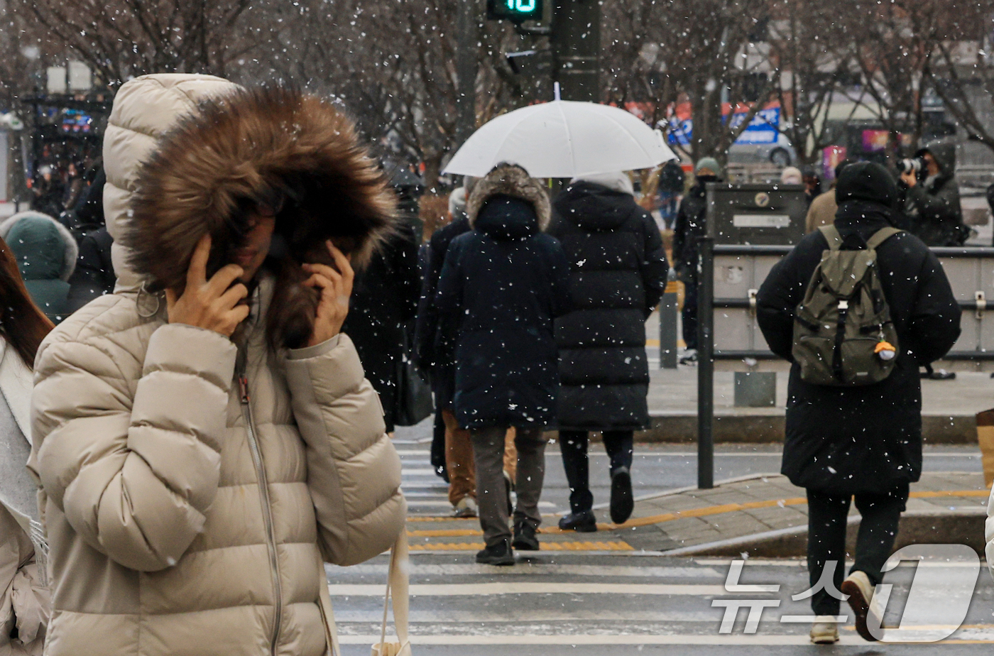 (서울=뉴스1) 이호윤 기자 = 눈이 내리는 12일 서울 세종대로사거리에서 시민들이 발걸음을 옮기고 있다. 2026.1.12/뉴스1