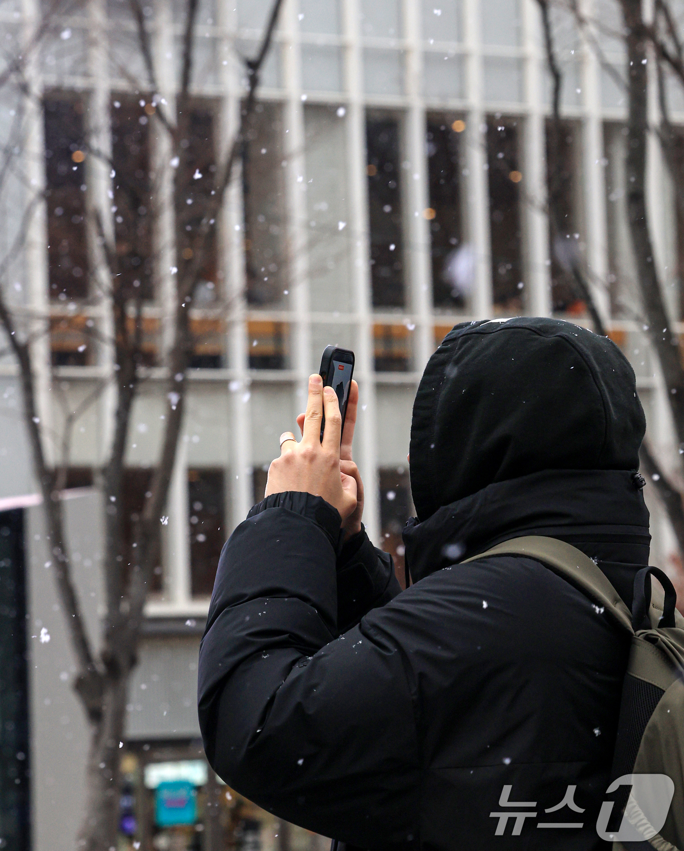 (서울=뉴스1) 이호윤 기자 = 눈이 내리는 12일 서울 세종대로사거리에서 시민이 걸을을 멈추고 눈을 바라보고 있다. 2026.1.12/뉴스1