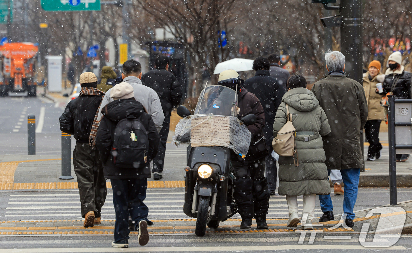 (서울=뉴스1) 이호윤 기자 = 눈이 내리는 12일 서울 세종대로사거리에서 시민들이 발걸음을 옮기고 있다. 2026.1.12/뉴스1