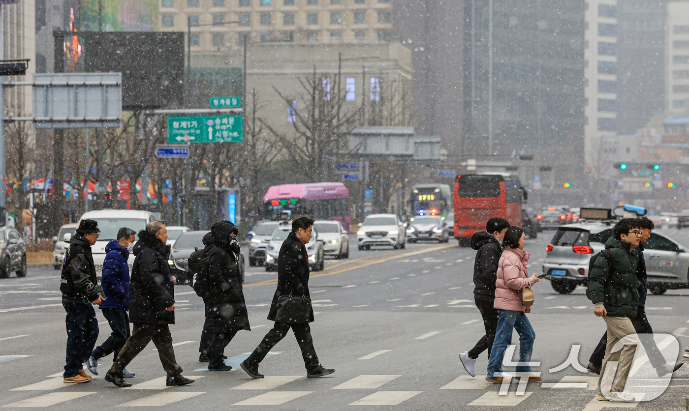 (서울=뉴스1) 이호윤 기자 = 눈이 내리는 12일 서울 세종대로사거리에서 시민들이 발걸음을 옮기고 있다. 2026.1.12/뉴스1