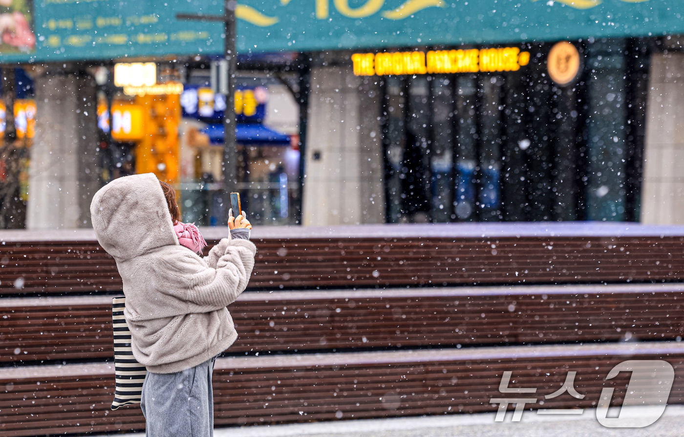 (서울=뉴스1) 이호윤 기자 = 눈이 내리는 12일 서울 광화문광장에서 외국인 관광객이 사진을 찍고 있다. 2026.1.12/뉴스1