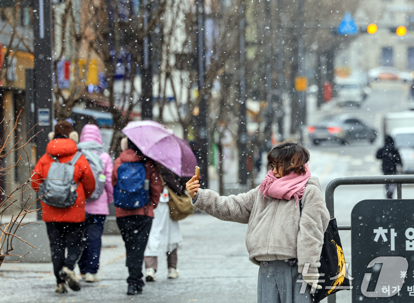 (서울=뉴스1) 이호윤 기자 = 눈이 내리는 12일 서울 광화문광장에서 외국인 관광객들이 사진을 찍고 있다. 2026.1.12/뉴스1