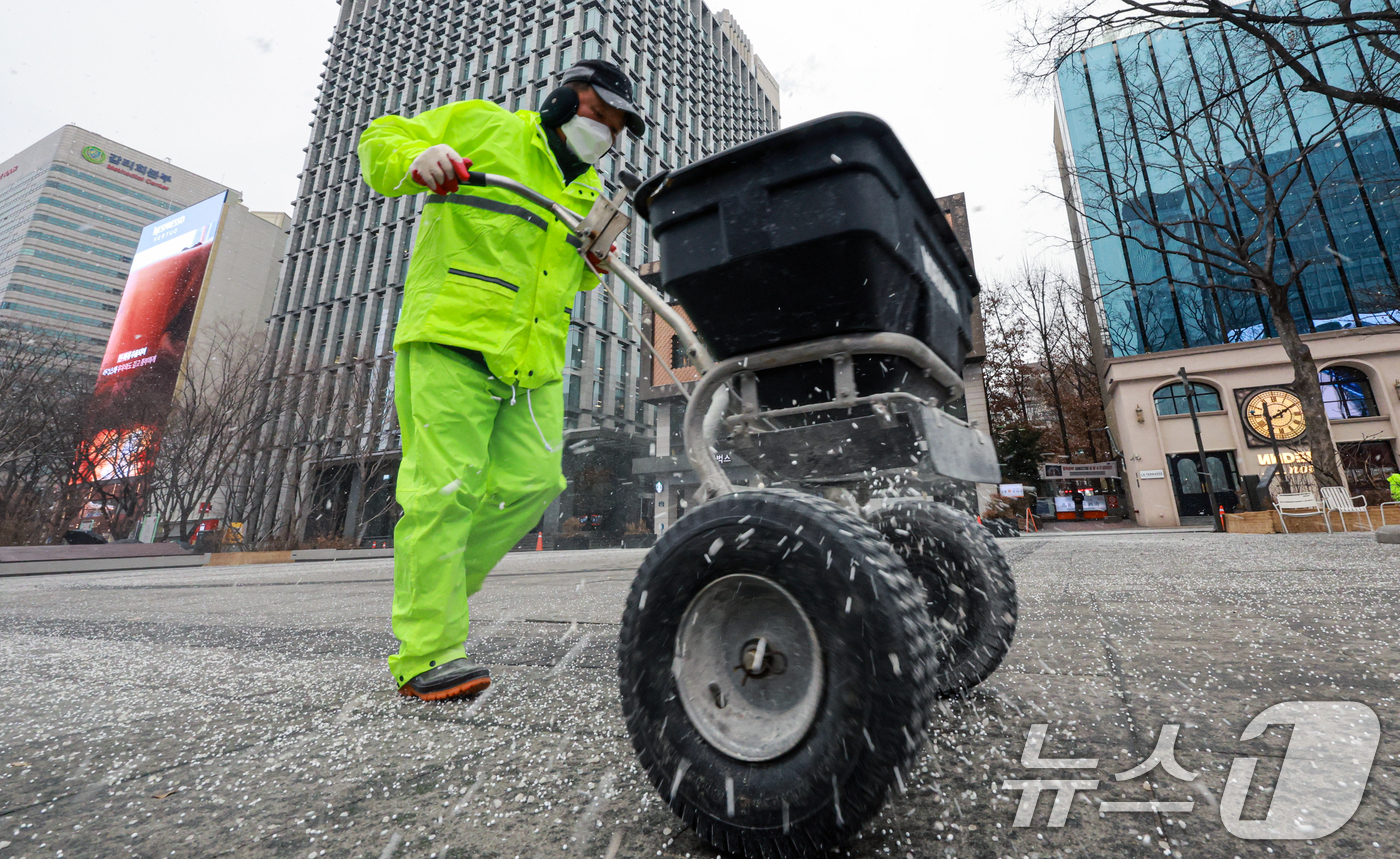 (서울=뉴스1) 이호윤 기자 = 눈이 내리는 12일 서울 광화문광장에서 작업자들이 염화칼슘을 뿌리고 있다. 2026.1.12/뉴스1