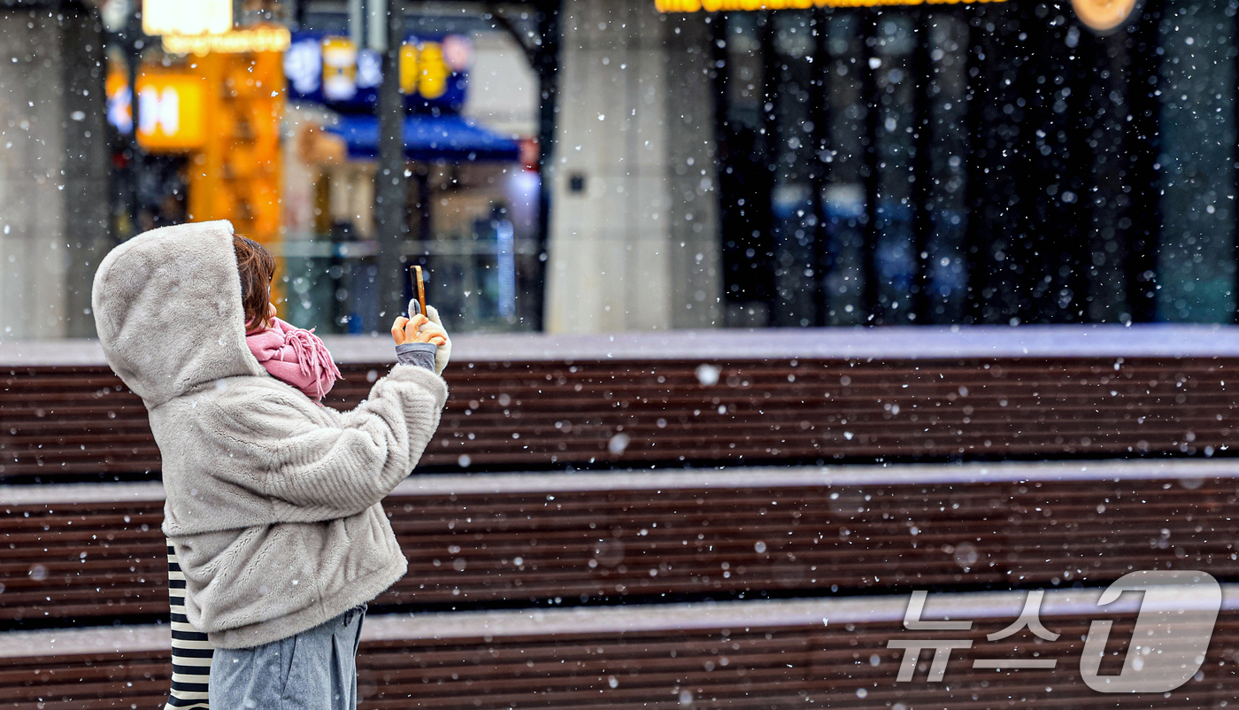 (서울=뉴스1) 이호윤 기자 = 눈이 내리는 12일 서울 광화문광장에서 외국인 관광객이 사진을 찍고 있다. 2026.1.12/뉴스1