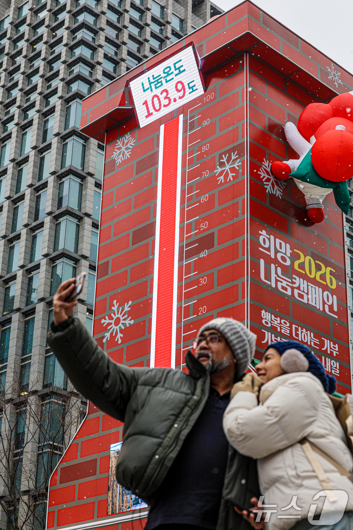 (서울=뉴스1) 이호윤 기자 = 12일 서울 종로구 광화문광장에서 외국인 관광객들이 사랑의 온도탑을 배경으로 사진을 찍고 있다.이날 사랑의열매 사회복지공동모금회는 ‘희망 2026 …