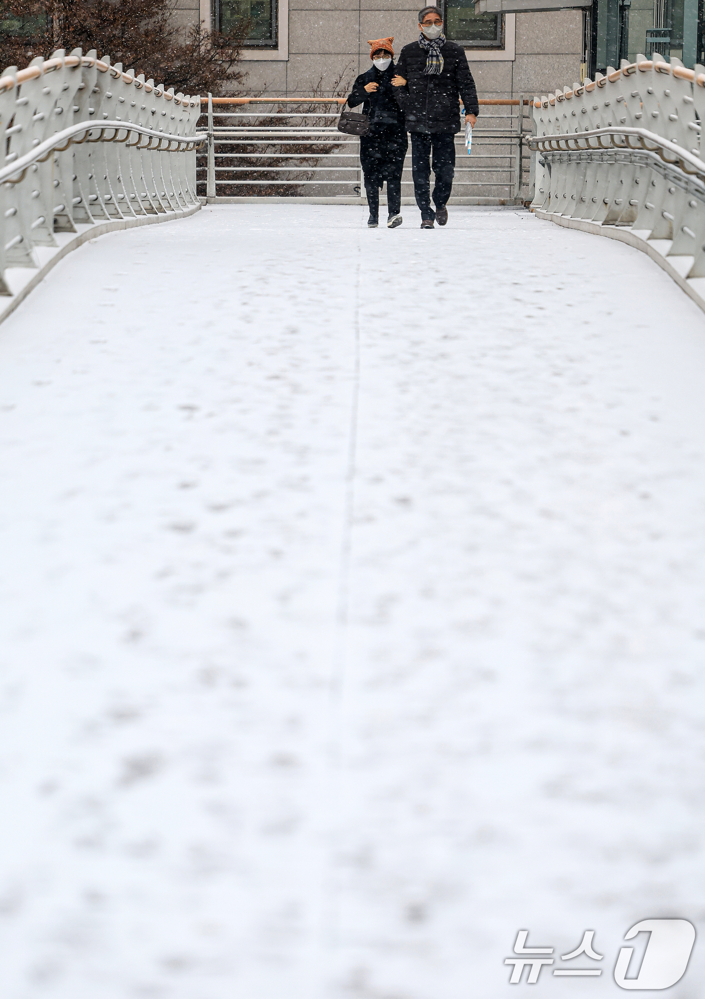 (서울=뉴스1) 이호윤 기자 = 눈이 내리는 12일 서울 마포구 인근 육교에서 시민들이 발걸음을 옮기고 있다. 2026.1.12/뉴스1