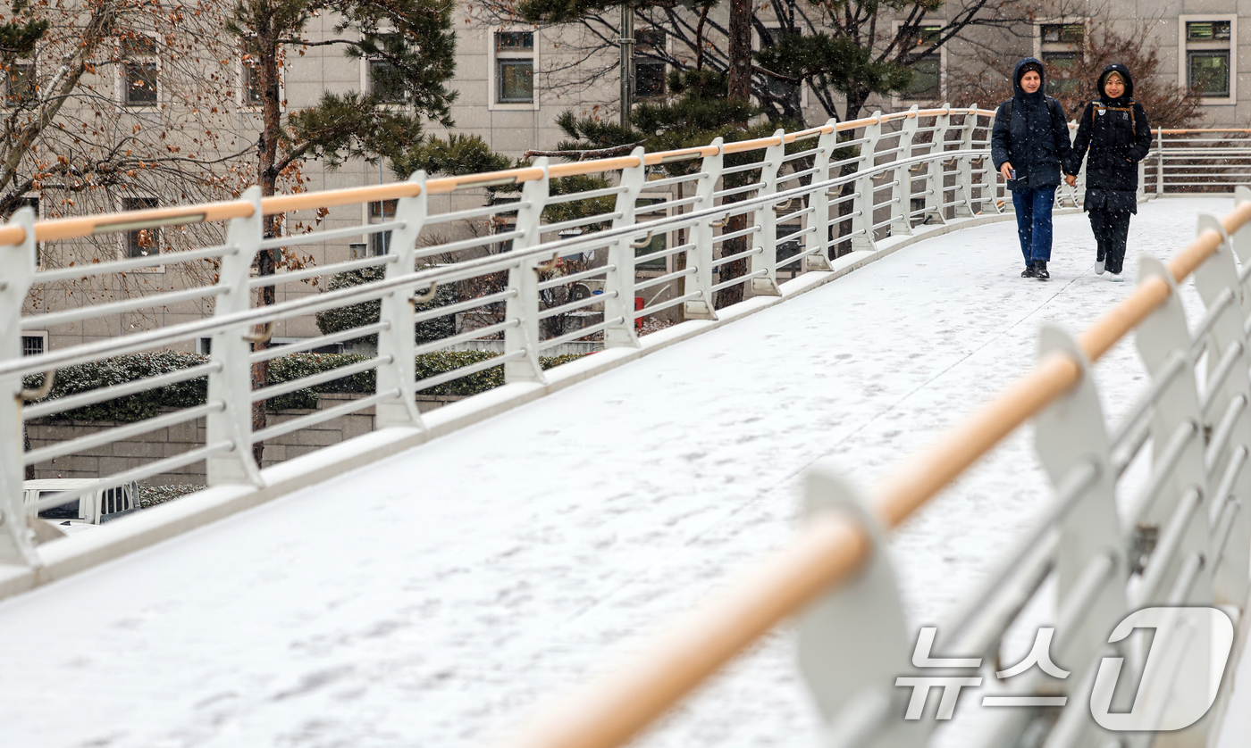 (서울=뉴스1) 이호윤 기자 = 눈이 내리는 12일 서울 마포구 인근 육교에서 외국인 관광객들이 발걸음을 옮기고 있다. 2026.1.12/뉴스1