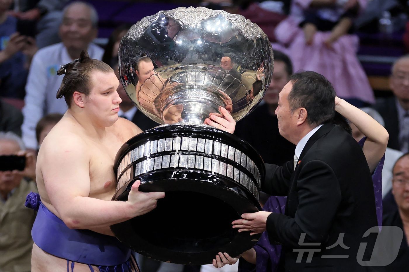 본문 이미지 - 우크라이나 출신 스모 선수 다닐로 야브후시신(왼쪽, 일본식 이름은 아오니시키 아라타)가 후쿠오카에서 열린 일본 프로 스모 규슈대회에서 우승한 뒤 다카이치 사나에 일본 총리의 보좌관으로부터 총리배 트로피를 받고 있다. 2025.11.23.ⓒ AFP=뉴스1