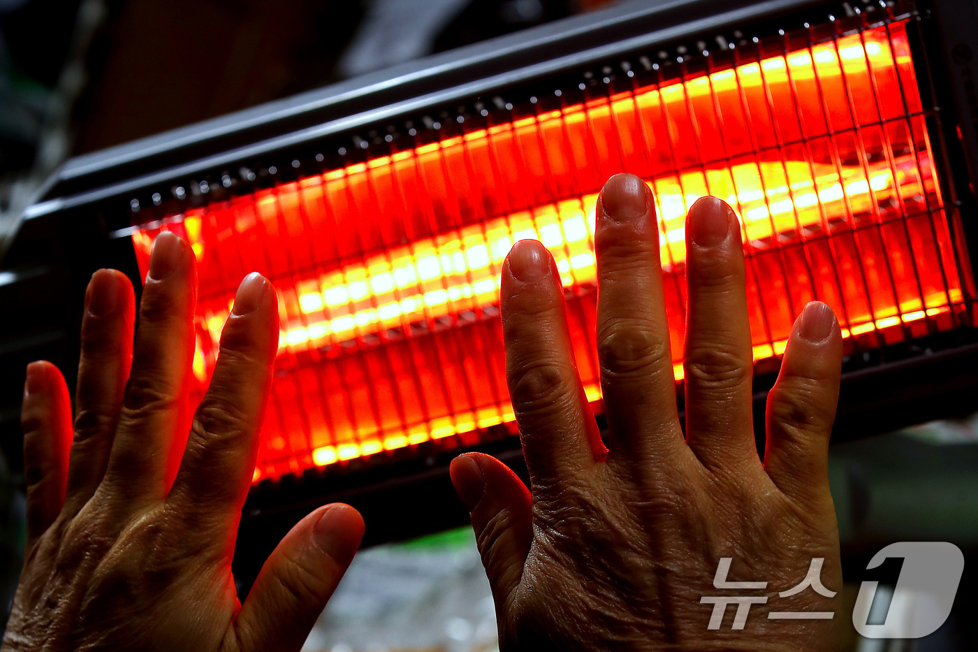 (대구=뉴스1) 공정식 기자 = 매서운 한파가 맹위를 떨친 14일 오전 대구 북구 칠성시장에서 영업을 준비하던 상인이 꽁꽁 언 손을 전기난로에 녹이고 있다. 2026.1.14/뉴스 …