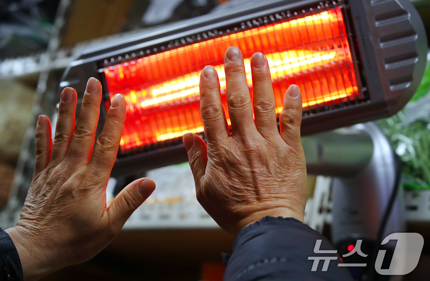 (대구=뉴스1) 공정식 기자 = 매서운 한파가 맹위를 떨친 14일 오전 대구 북구 칠성시장에서 영업을 준비하던 상인이 꽁꽁 언 손을 전기난로에 녹이고 있다. 2026.1.14/뉴스 …