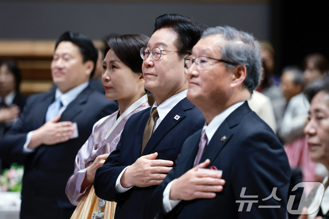 (나라(일본)=뉴스1) 이재명 기자 = 이재명 대통령과 김혜경 여사가 14일 일본 나라현의 한 호텔에서 열린 간사이 동포 간담회에서 국민의례를 하고 있다. 2026.1.14/뉴스1 …