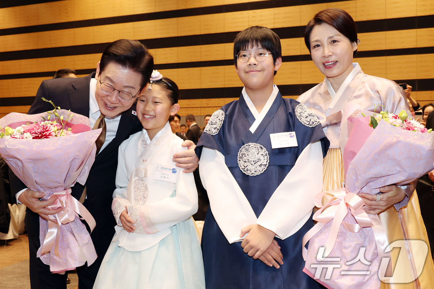 (나라(일본)=뉴스1) 이재명 기자 = 이재명 대통령과 김혜경 여사가 14일 일본 나라현의 한 호텔에서 열린 간사이 동포 간담회에서 화동들에게 꽃다발을 받은 뒤 기념촬영을 하고 있 …