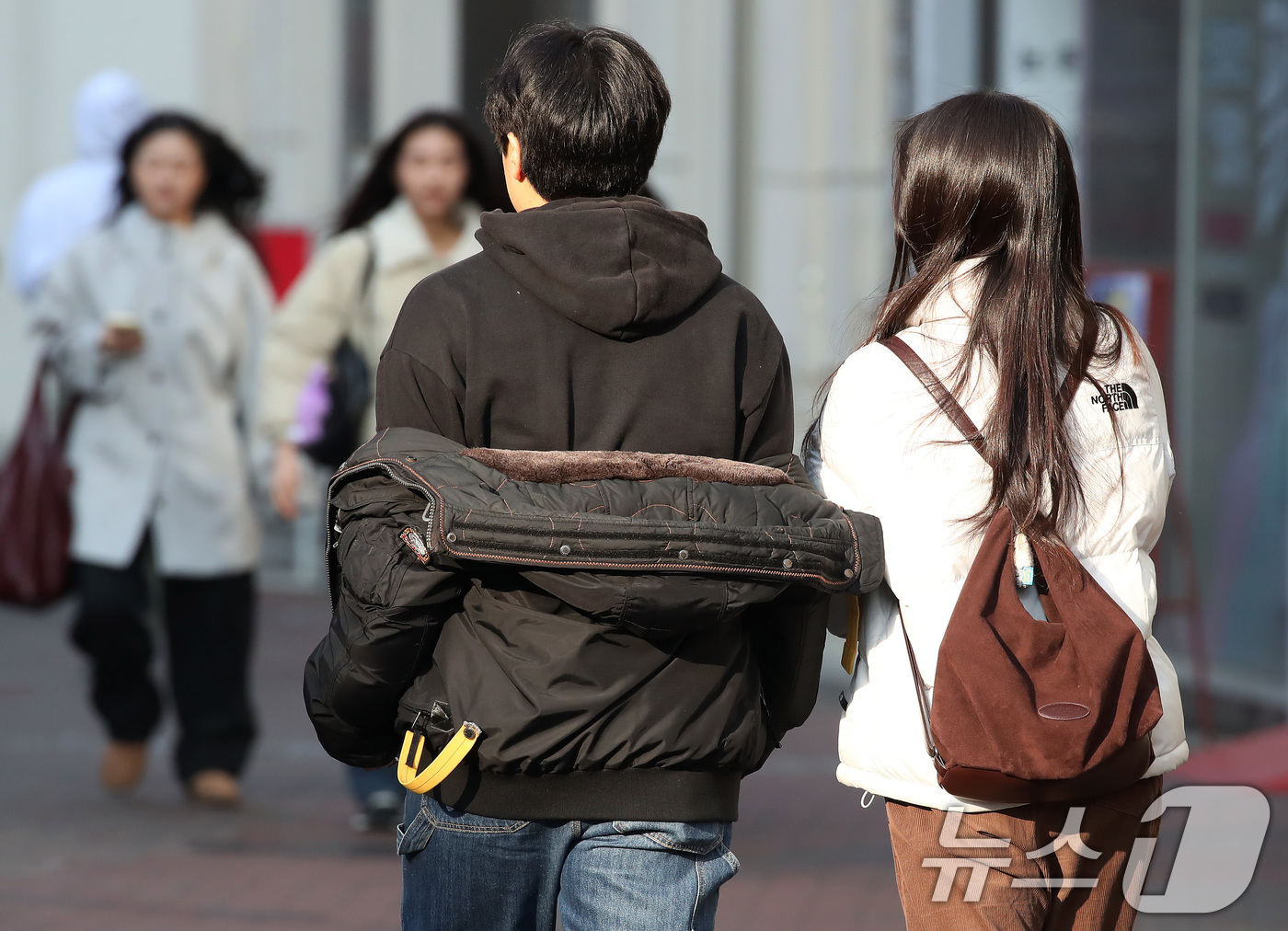 (대구=뉴스1) 공정식 기자 = 하루 사이 기온이 크게 오른 15일 오후 대구 중구 동성로에서 한 시민이 외투를 반쯤 벗어 걸친 채 걸어가고 있다. 2026.1.15/뉴스1