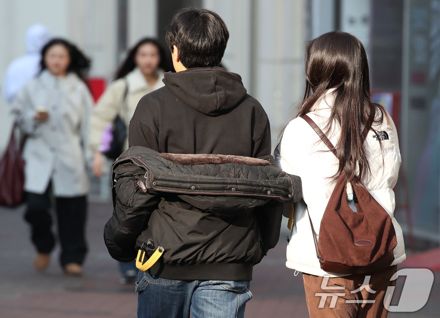 본문 이미지 - 15일 오후 대구 중구 동성로에서 한 시민이 외투를 반쯤 벗어 걸친 채 걸어가고 있다. 2026.1.15/뉴스1 ⓒ News1 공정식 기자