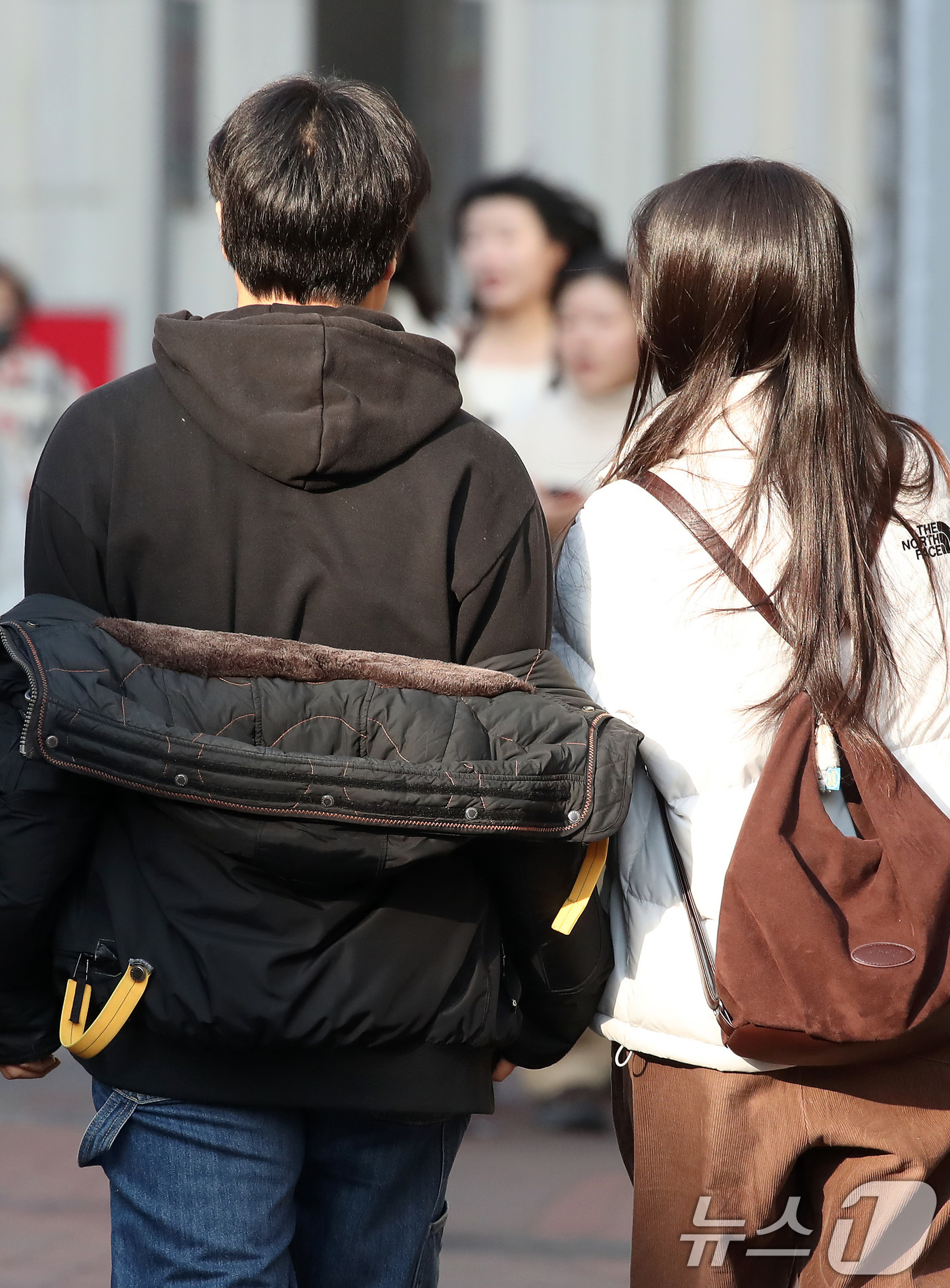 (대구=뉴스1) 공정식 기자 = 하루 사이 기온이 크게 오른 15일 오후 대구 중구 동성로에서 한 시민이 외투를 반쯤 벗어 걸친 채 걸어가고 있다. 2026.1.15/뉴스1