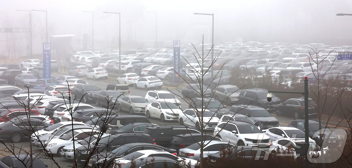 본문 이미지 - 세종을 비롯한 충청권·전북 지역에 초미세먼지 위기경보 ‘관심’ 단계가 발령되면서 16일 정부세종청사 출입구에서는 차량 2부제가 시행되어 홀수차량 출입을 통제하는 가운데 출입이 막힌 공무원들의 차량이 통제가 없는 옥외 주차장을 가득 메우고 있다.  2026.1.16/뉴스1 ⓒ News1 김기남 기자
