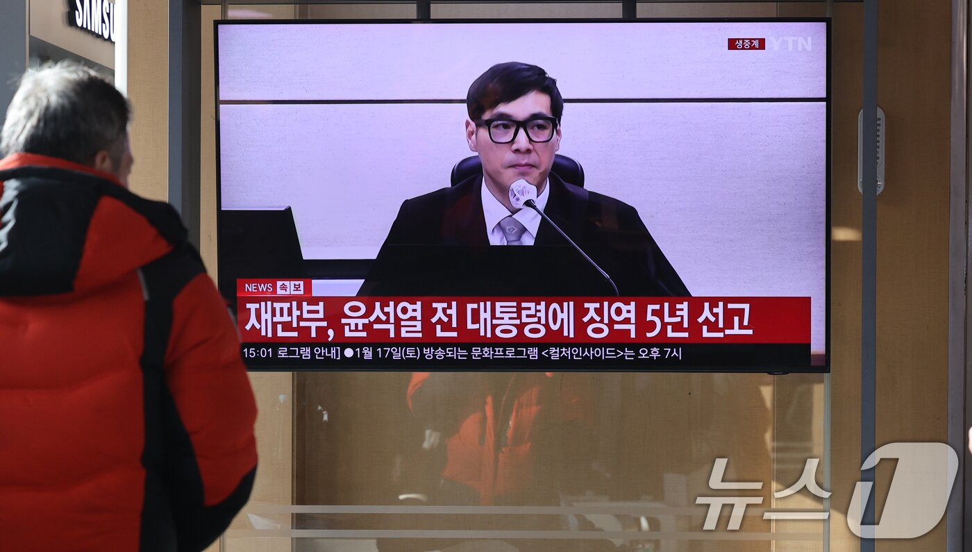본문 이미지 - 16일 오후 서울역에서 시민들이 체포 방해와 국무위원 심의권 침해 등 혐의로 기소된 윤석열 전 대통령에 대한 1심 선고 생중계를 지켜보고 있다. 서울 서초구 중앙지방법원에서 열린 1심 선고에서 백대현 부장판사가 판결문을 낭독한 뒤 징역 5년을 선고하는 모습. 2026.1.16/뉴스1 ⓒ News1 이광호 기자