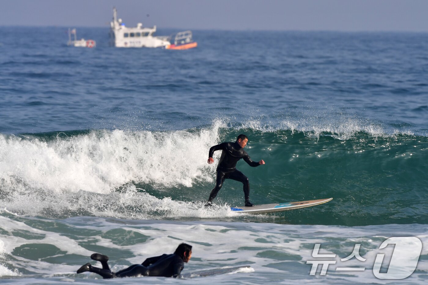 본문 이미지 - 18일 경북 포항시 북구 흥해읍 용한리 해수욕장에서 서퍼들이 겨울 파도를 타고 있는 가운데 포항해양경찰서 연안구조정이 연안 순찰을 하고 있다. 2026.1.18/뉴스1 ⓒ News1 최창호 기자