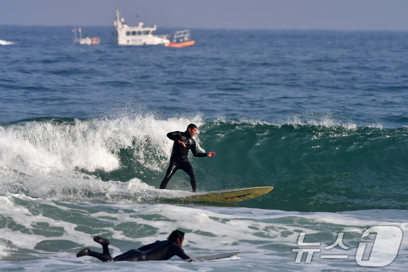 (포항=뉴스1) 최창호 기자 = 18일 경북 포항시 북구 흥해읍 용한리 해수욕장에서 서퍼들이 겨울 파도를 타고 있는 가운데 포항해양경찰서 연안구조정이 연안 순찰을 하고 있다. 20 …