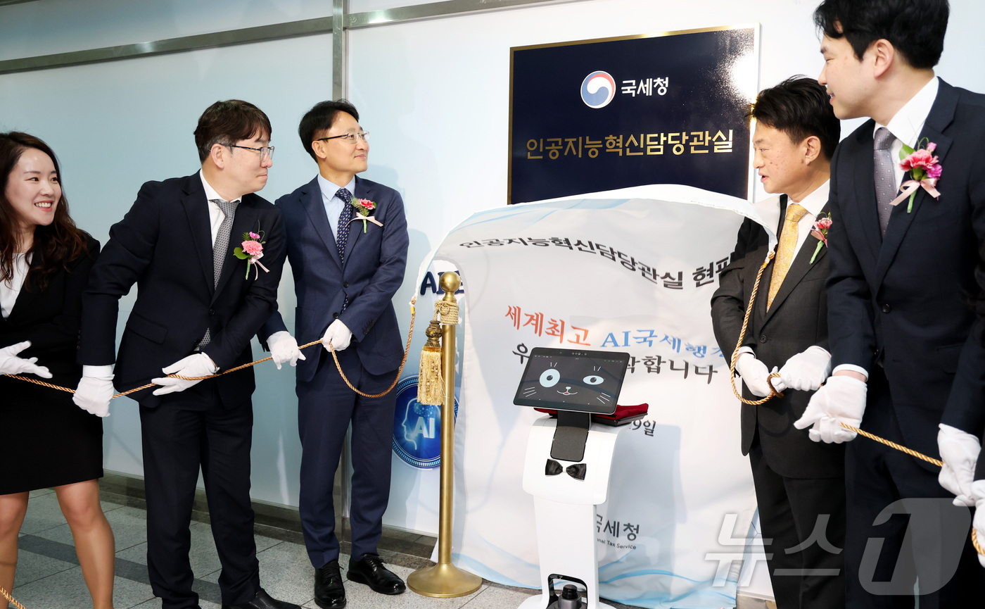 (세종=뉴스1) 김기남 기자 = 임광현 국세청장(왼쪽 세번째)이 19일 세종시 나성동 SM타워에 문을 연 AI혁신담당관실 현판식에 참석하여 로봇 카이(K-AI) 및 관계자들과 AI …