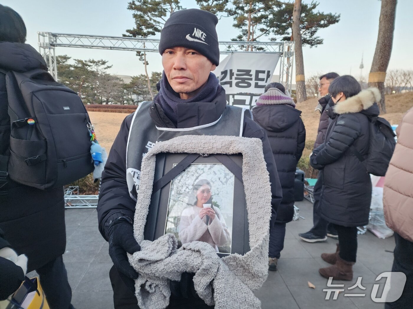 본문 이미지 - 2일 고 뚜안의 아버지 부반숭 씨가 목도리로 감싼 딸의 영정을 안고 있다. 2026.01.02/ⓒ 뉴스1 권진영 기자