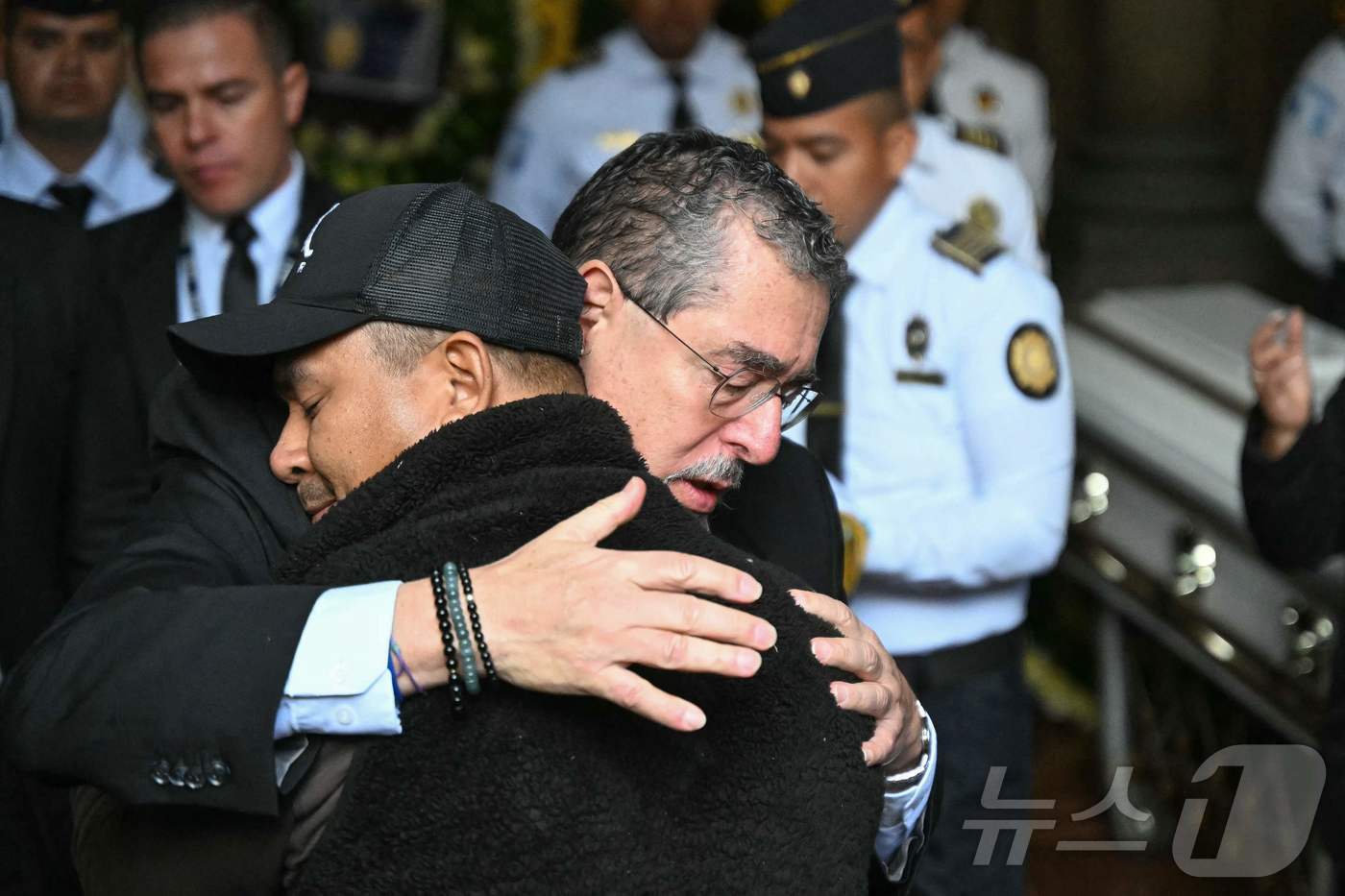 본문 이미지 - 19일(현지시간) 과테말라시티 내무부 청사에서 열린 순직 경찰관 장례식에서 베르나르도 아레발루 과테말라 대통령이 유족을 안아주고 있다. 2026.01.19. ⓒ AFP=뉴스1 ⓒ News1 이정환 기자