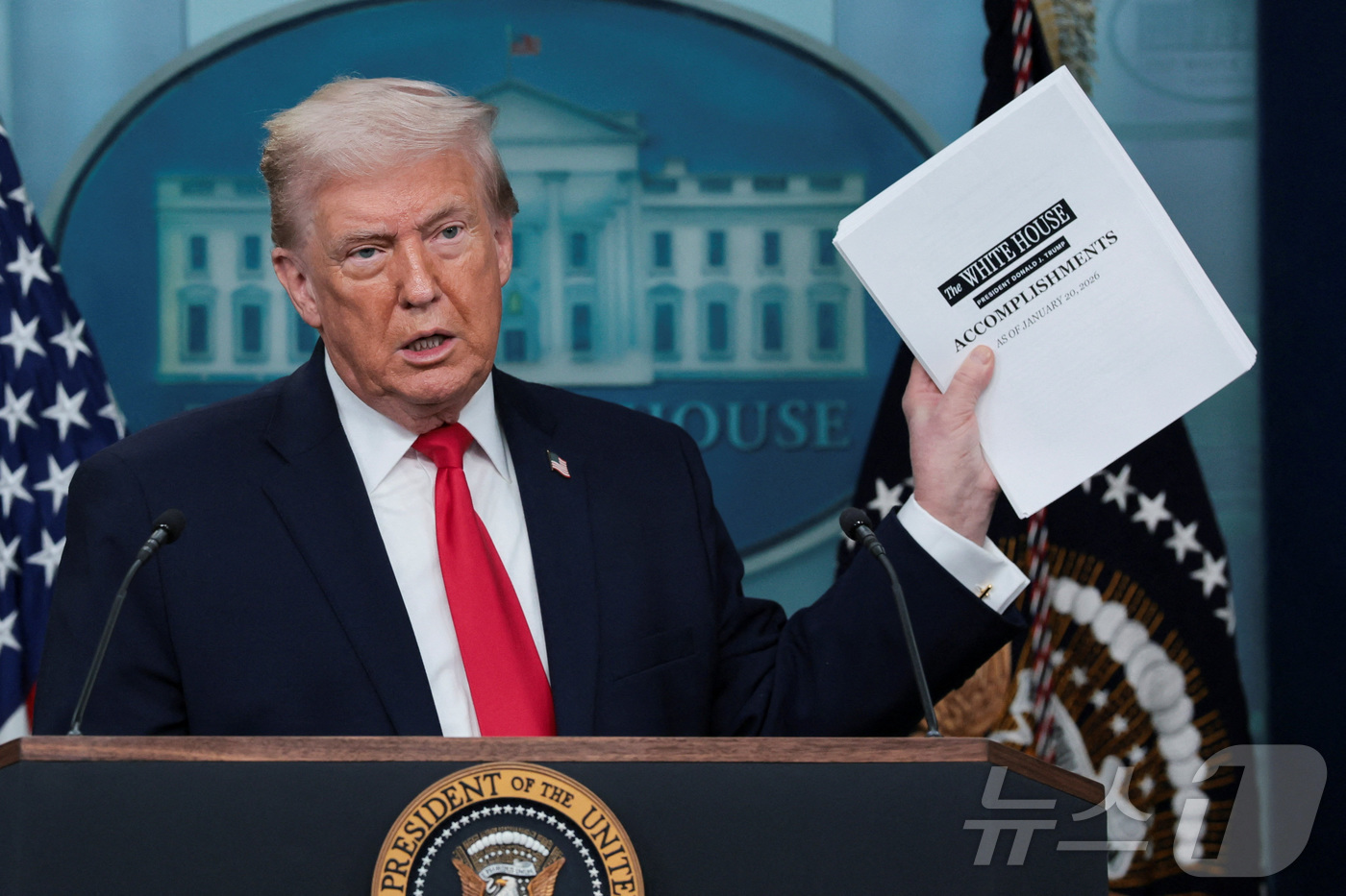 (워싱턴DC 로이터=뉴스1) 류정민 특파원 = 도널드 트럼프 미국 대통령이 두 번째 임기 1주년을 맞은 20일(현지시간) 워싱턴DC 백악관에서 자신의 성과를 모은 문서를 들어 보이 …
