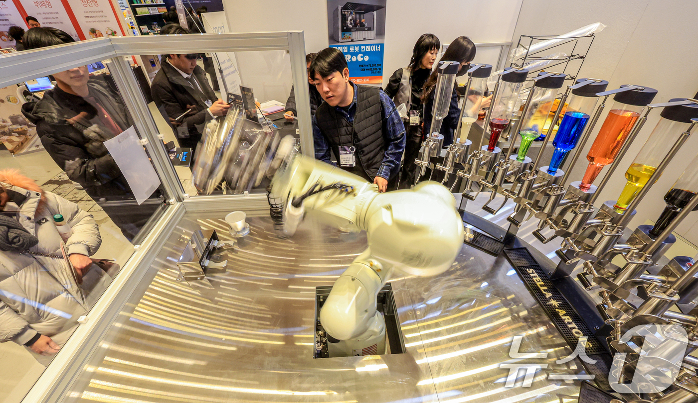 (서울=뉴스1) 이호윤 기자 = 21일 서울 강남구 코엑스에서 열린 ‘2026 호텔페어’를 찾은 관람객들이 칵테일 제작 로봇을 살펴보고 있다.이번 전시는 호텔 운영 솔루션을 비롯해 …