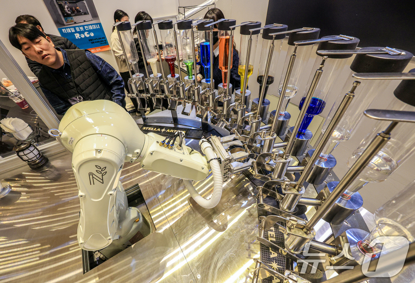 (서울=뉴스1) 이호윤 기자 = 21일 서울 강남구 코엑스에서 열린 ‘2026 호텔페어’를 찾은 관람객들이 칵테일 제작 로봇을 살펴보고 있다.이번 전시는 호텔 운영 솔루션을 비롯해 …