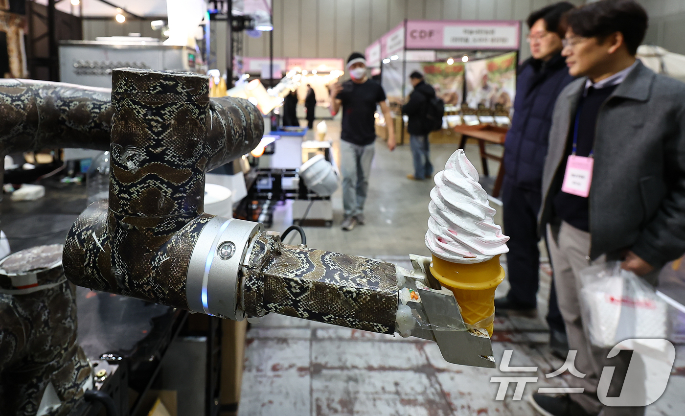 (고양=뉴스1) 김도우 기자 = 22일 경기 고양시 킨텍스에서 열린 2026 카페디저트페어에서 관람객들이 로봇이 전달하는 아이스크림을 지켜보고 있다. 2026.1.22/뉴스1