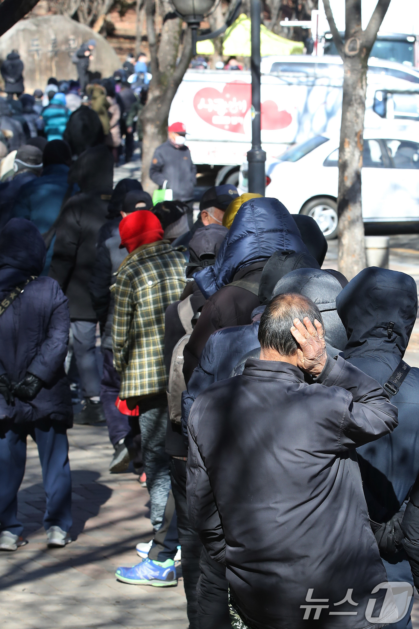(대구=뉴스1) 공정식 기자 = 매서운 한파가 몰아친 22일 대구 달서구 두류공원 '사랑해밥차' 무료급식소를 찾은 사람들이 줄지어 점심 배식을 기다리고 있다. 2026.1.22/뉴 …