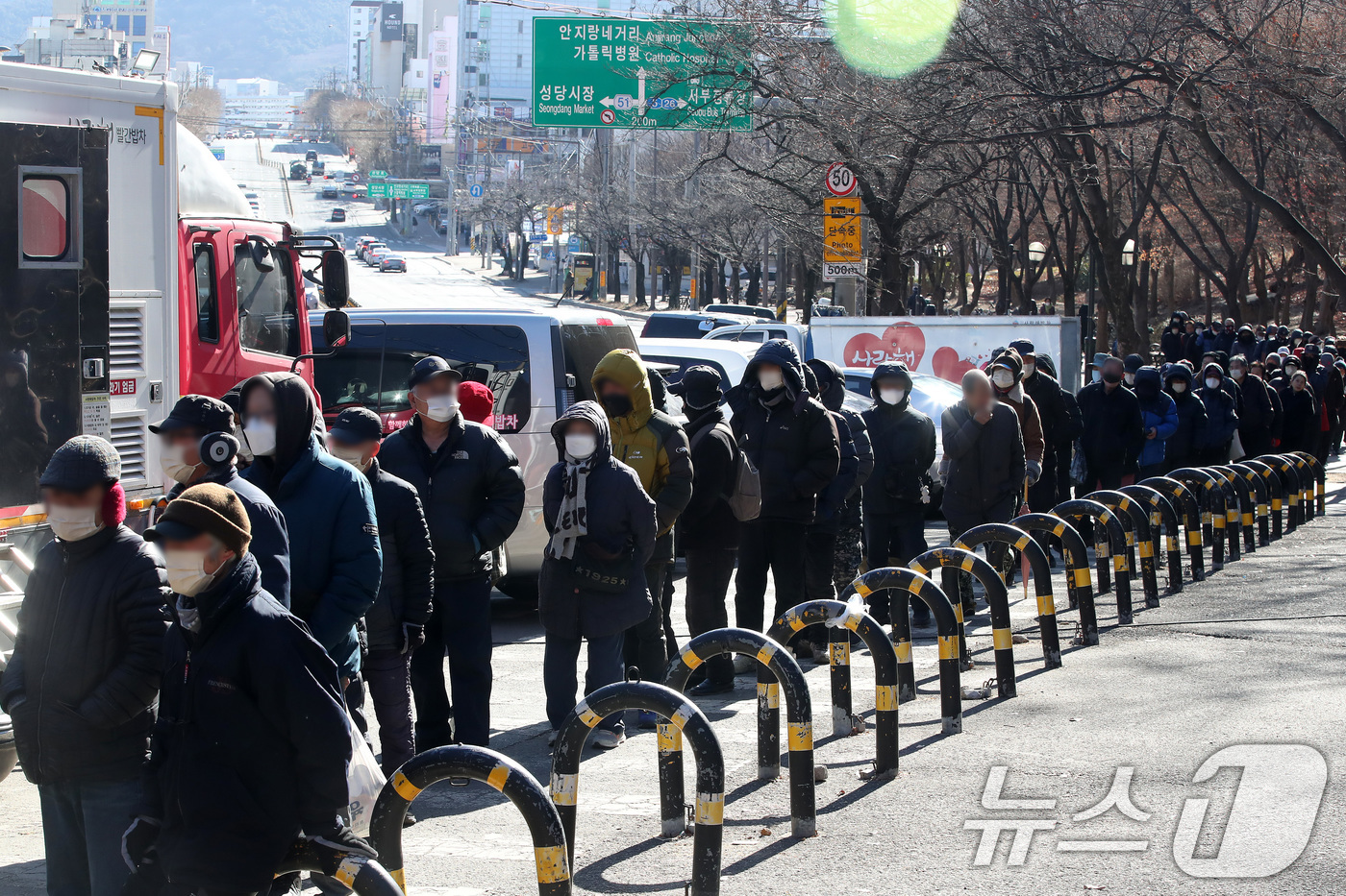(대구=뉴스1) 공정식 기자 = 매서운 한파가 몰아친 22일 대구 달서구 두류공원 '사랑해밥차' 무료급식소를 찾은 사람들이 줄지어 점심 배식을 기다리고 있다. 2026.1.22/뉴 …