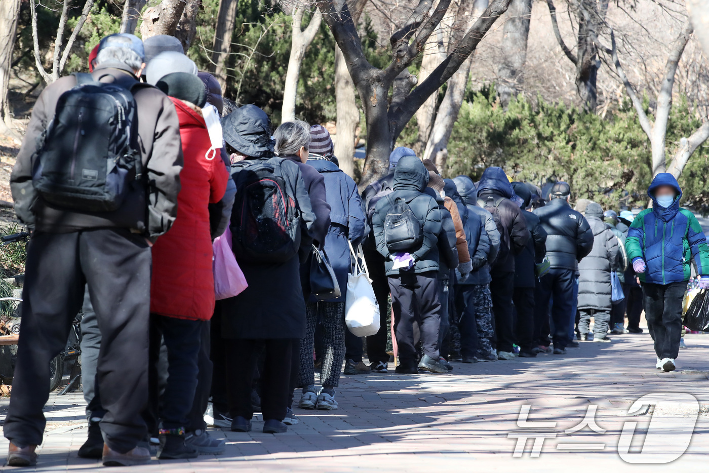 (대구=뉴스1) 공정식 기자 = 매서운 한파가 몰아친 22일 대구 달서구 두류공원 '사랑해밥차' 무료급식소를 찾은 사람들이 줄지어 점심 배식을 기다리고 있다. 2026.1.22/뉴 …