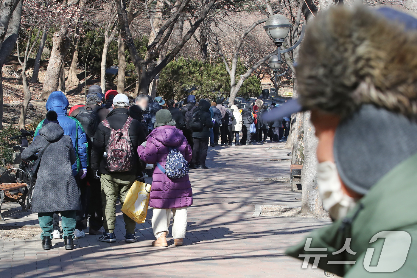 (대구=뉴스1) 공정식 기자 = 매서운 한파가 몰아친 22일 대구 달서구 두류공원 '사랑해밥차' 무료급식소를 찾은 사람들이 줄지어 점심 배식을 기다리고 있다. 2026.1.22/뉴 …