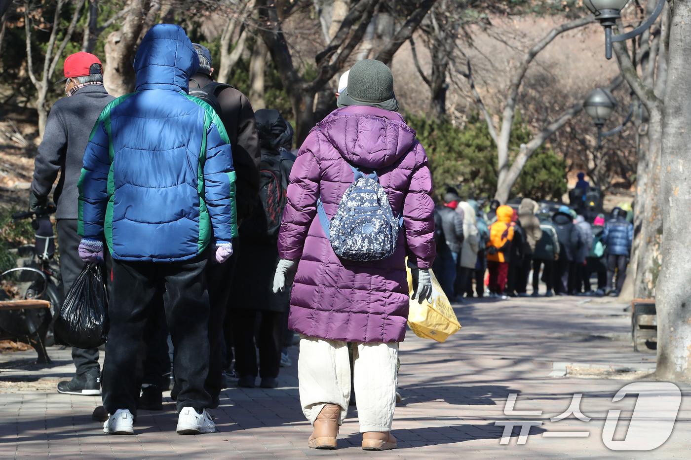 (대구=뉴스1) 공정식 기자 = 매서운 한파가 몰아친 22일 대구 달서구 두류공원 '사랑해밥차' 무료급식소를 찾은 사람들이 줄지어 점심 배식을 기다리고 있다. 2026.1.22/뉴 …