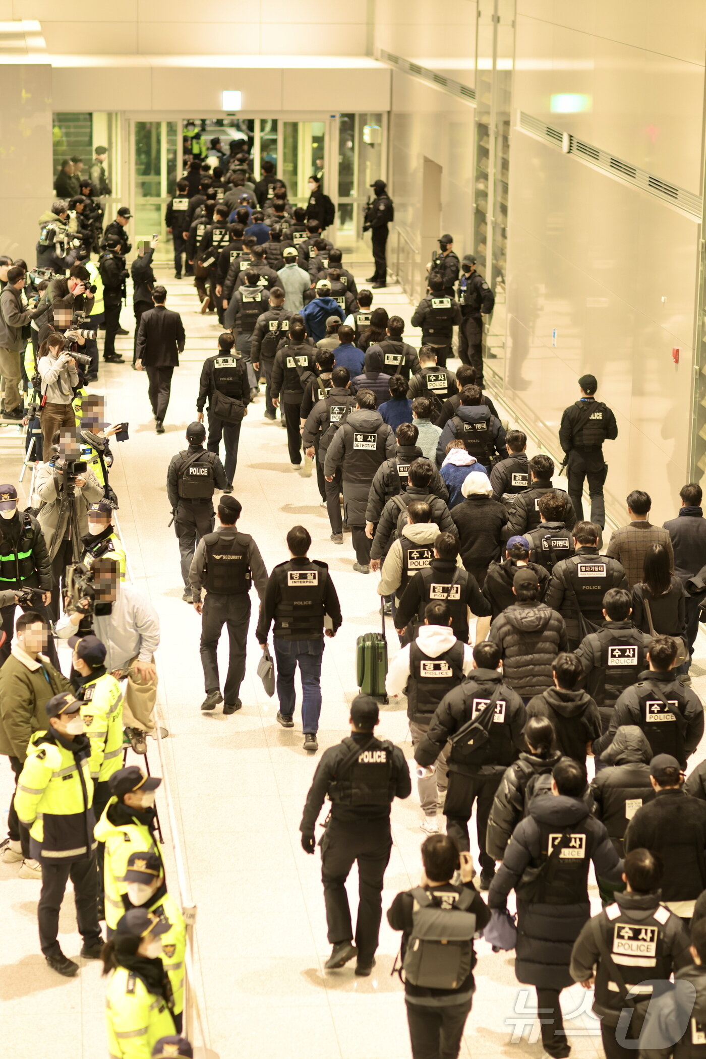 본문 이미지 - 캄보디아를 거점으로 대규모 스캠 범죄를 저지른 한국 국적 피의자 73명이 23일 오전 인천국제공항 2터미널을 통해 강제 송환되고 있다. (부산경찰청 제공. 재판매 및 DB 금지) 2026.1.23/뉴스1 ⓒ News1 윤일지 기자