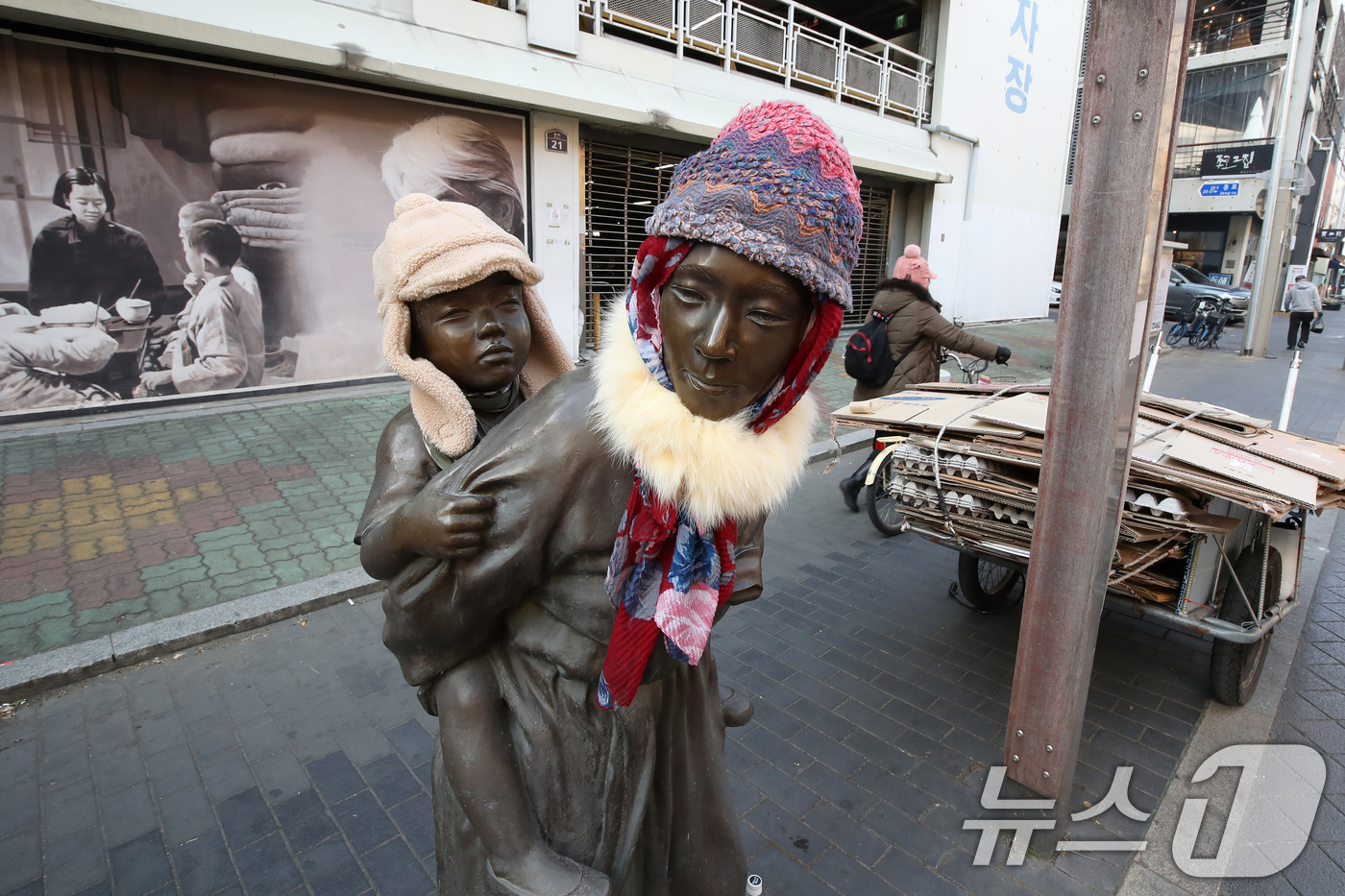(대구=뉴스1) 공정식 기자 = 동장군이 기승을 부린 23일 오후 대구 중구 종로 약령시 인근에 세워진 '엄마의 마음' 조각상(이현우 작)에 시민들이 씌워놓은 방한모와 목도리가 눈 …
