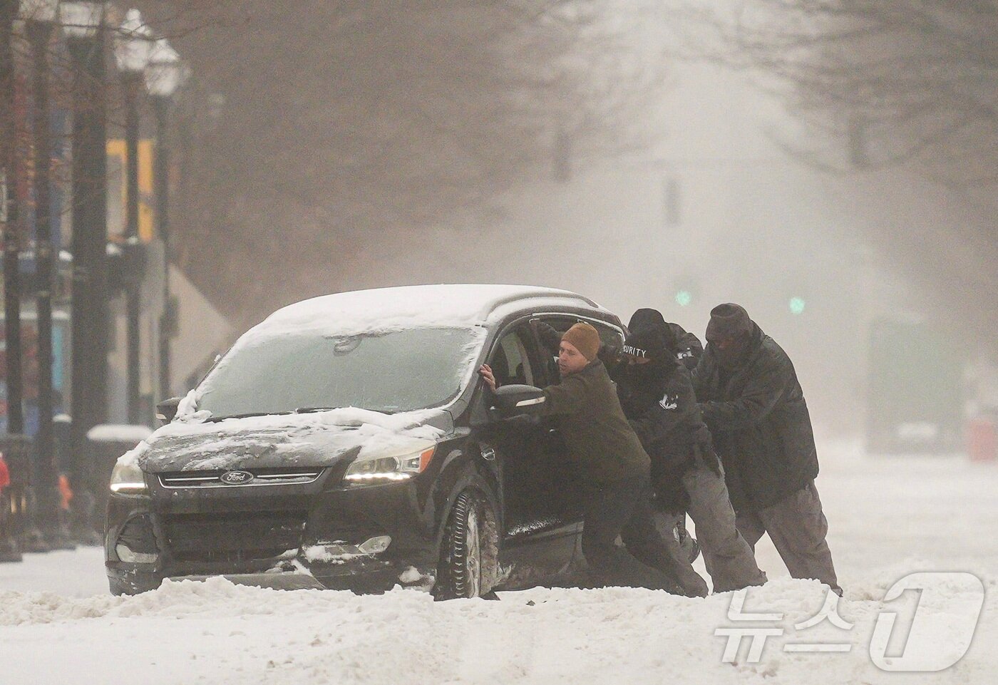본문 이미지 - 25일(현지시간) 미국 전역에 걸쳐 겨울 폭풍이 몰아친 가운데, 켄터키주 루이빌의 한 도로에서 남성들이 눈에 갇힌 차량을 빼내려 안간힘을 쓰고 있다. 2026.01.25. ⓒ 로이터=뉴스1 ⓒ News1 류정민 특파원