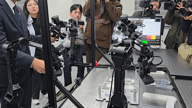 본문 이미지 - 26일 전북대 '피지컬 AI 실증랩' 개소식에서 배경훈 부총리 겸 과학기술정보통신부 장관이 사람 손 동작을 학습하는 로봇 팔을 조작해보고 있다. 실증랩은 이같은 데이터 수집 및 파운데이션 모델 고도화를 맡은 '이노베이션 존'과, 개발된 결과를 공정에서 검증해보는 '프로덕션 존'을 완비했다./뉴스1 ⓒNews1 윤주영 기자