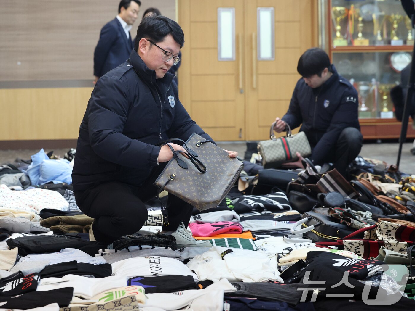 본문 이미지 - 27일 오전 인천 중구 인천본부세관에서 열린 '1200억원대 위조 명품 판매 쇼핑몰 운영조직 적발' 브리핑에서 직원들이 압수품을 살펴보고 있다. 2026.1.27/뉴스1 ⓒ News1 황기선 기자