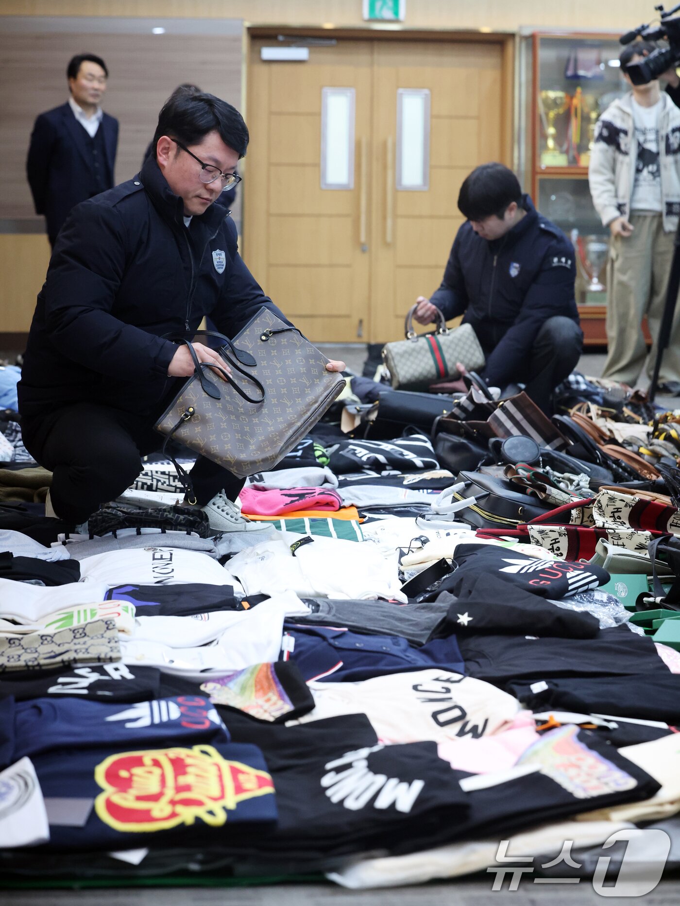 본문 이미지 - 27일 오전 인천 중구 인천본부세관에서 열린 '1200억원대 위조 명품 판매 쇼핑몰 운영조직 적발' 브리핑에서 직원들이 압수품을 살펴보고 있다.  2026.1.27/뉴스1 ⓒ News1 황기선 기자