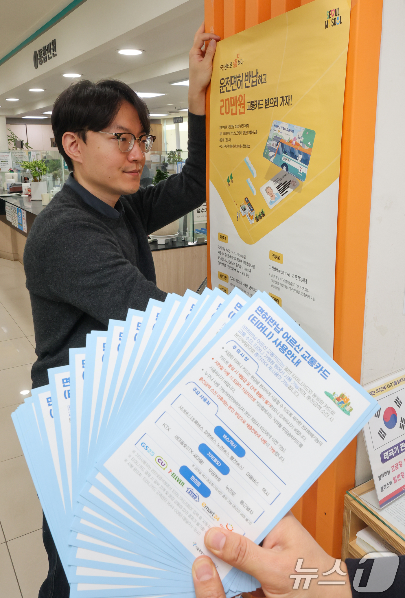 (서울=뉴스1) 안은나 기자 = 고령 운전자의 교통사고 예방을 위한 운전면허 자진 반납 신청을 하루 앞둔 27일 서울 송파구 석촌동주민센터에서 직원이 안내문을 부착하고 있다.서울시 …