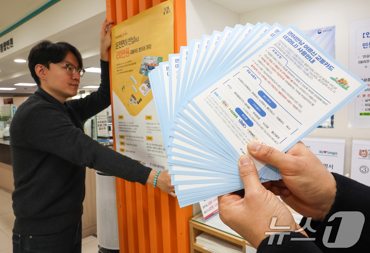 (서울=뉴스1) 안은나 기자 = 고령 운전자의 교통사고 예방을 위한 운전면허 자진 반납 신청을 하루 앞둔 27일 서울 송파구 석촌동주민센터에서 직원이 안내문을 부착하고 있다.서울시 …