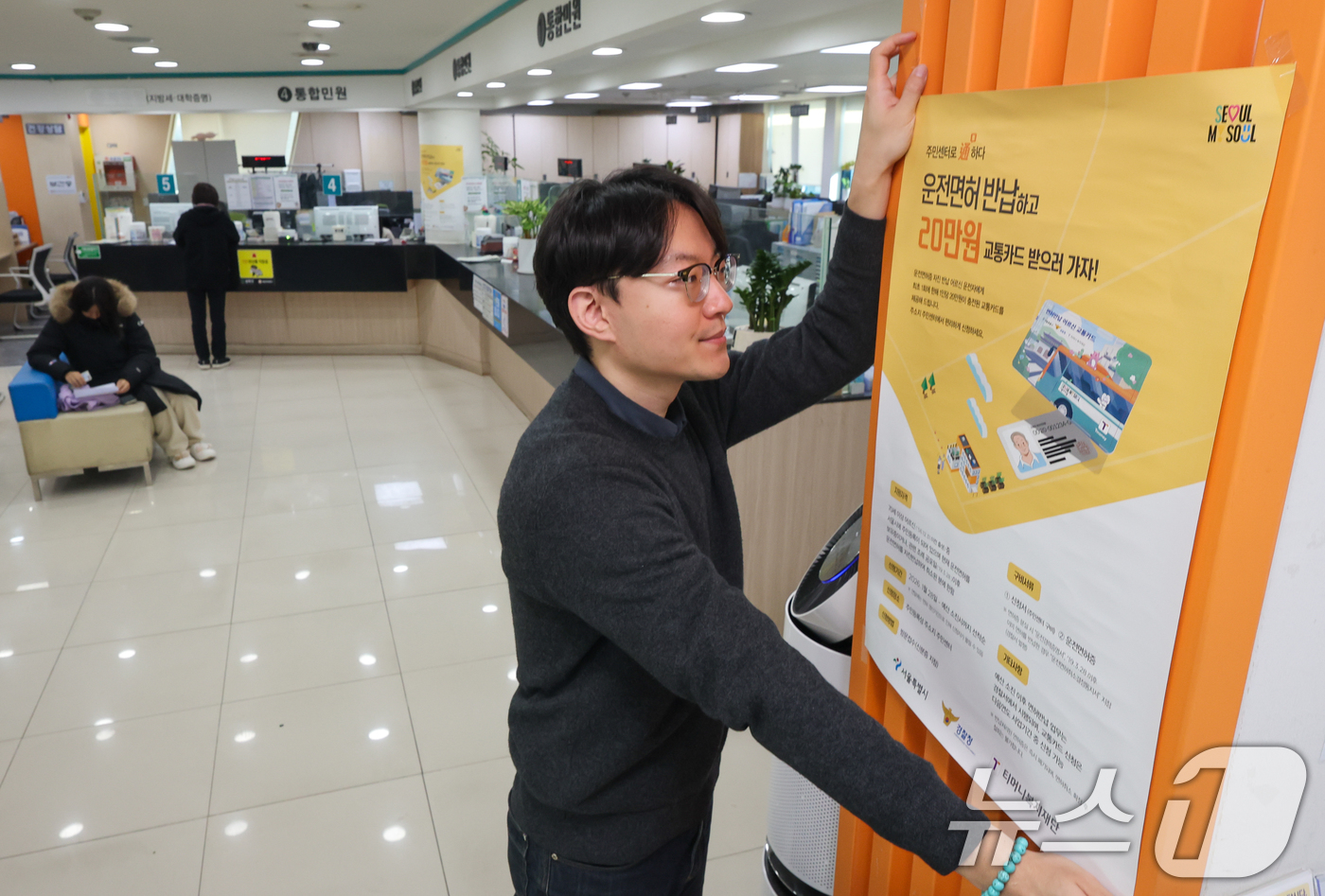 (서울=뉴스1) 안은나 기자 = 고령 운전자의 교통사고 예방을 위한 운전면허 자진 반납 신청을 하루 앞둔 27일 서울 송파구 석촌동주민센터에서 직원이 안내문을 부착하고 있다.서울시 …