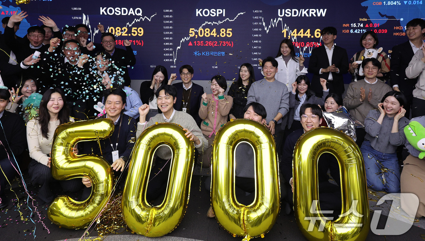 (서울=뉴스1) 박지혜 기자 = 코스피가 종가 기준 사상 처음 5000선을 돌파한 27일 오후 서울 영등포구 KB국민은행 딜링룸에서 직원들이 축하 세리머니를 하고 있다.이날 코스피 …
