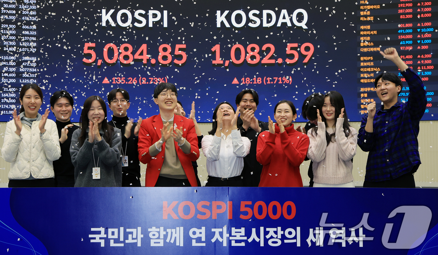 (서울=뉴스1) 이호윤 기자 = 한국 증시 최초로 종가 기준 코스피 5000을 달성한 27일 서울 영등포구 한국거래소에서 직원들이 코스피 종가가 표시된 전광판을 배경으로 세레머니를 …