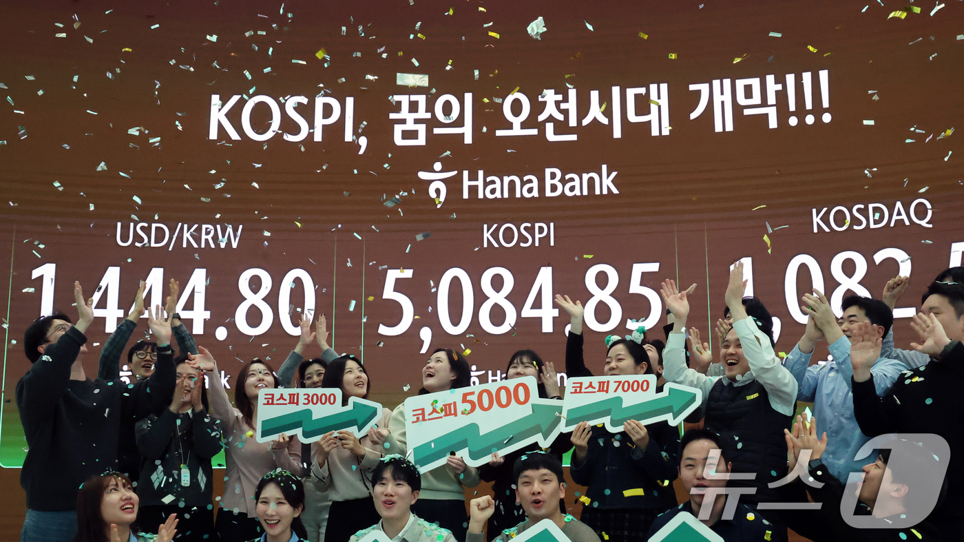 (서울=뉴스1) 황기선 기자 = 코스피가 종가 기준 사상 처음 5000선을 돌파한 27일 오후 서울 중구 하나은행 본점 딜링룸에서 직원들이 축하 세리머니를 하고 있다.이날 코스피지 …